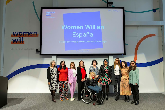 10 mujeres, 1 de ellas en silla de ruedas, posan a la cámara debajo de una pantalla gigante que dice Women Will en España.