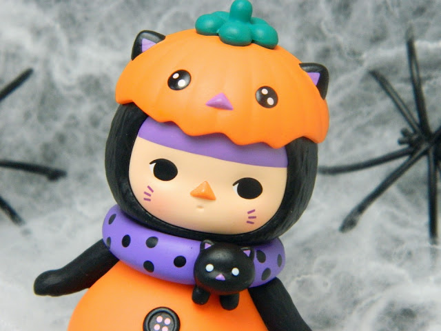 A photo showing a figure of a baby dressed in a black cat pumpkin costume for Halloween
