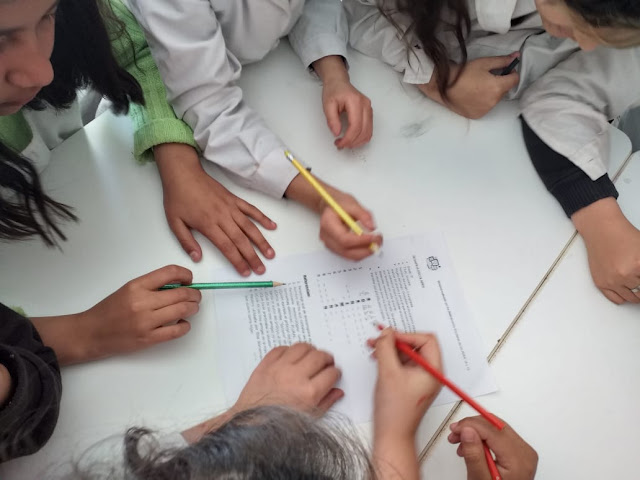 manos de alumnos con lapices escribiendo una produccion conjunta