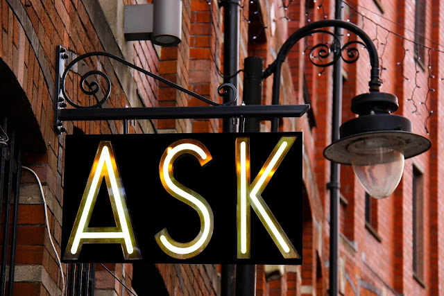 photo of "ASK" sign hanging from brick building