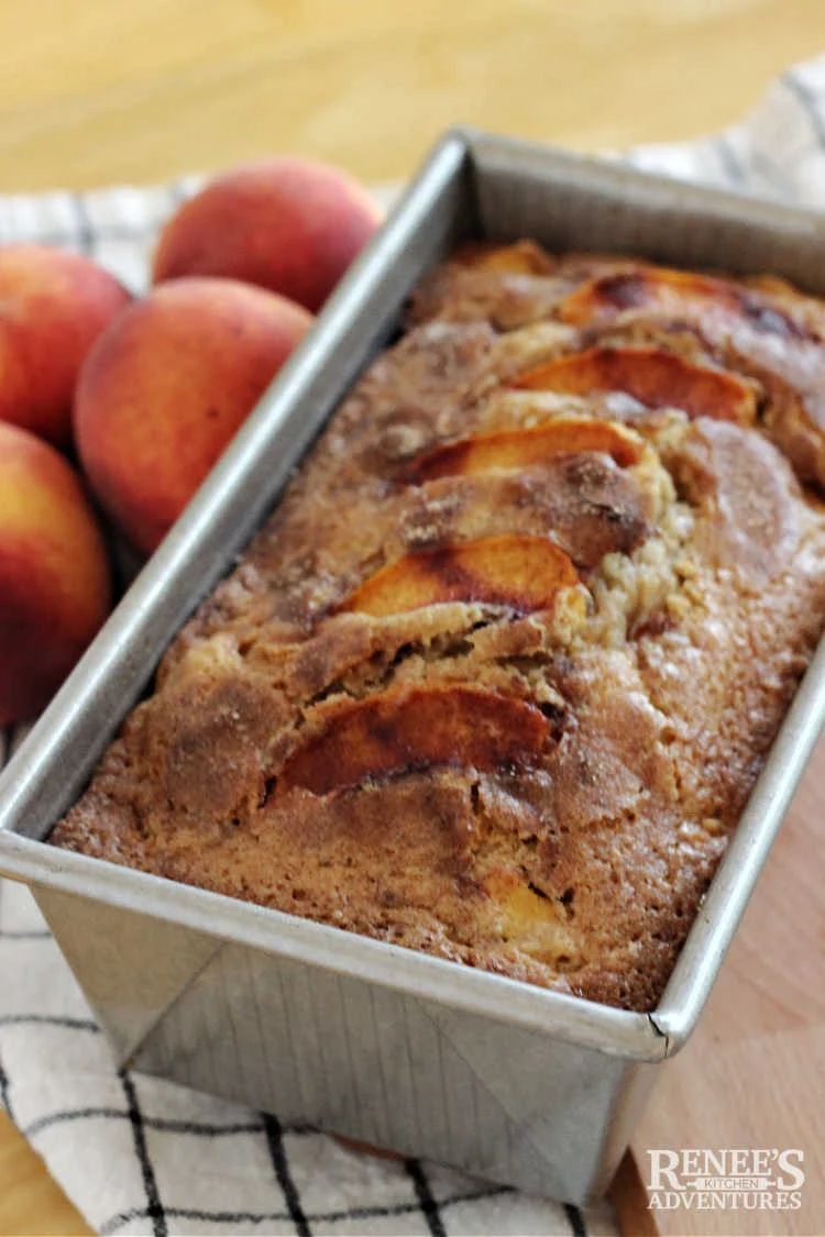 Peach bread in pan with peaches on the side