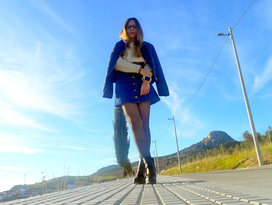 Falda denim acamapanda, jersey de punto rasgado, cazadora biker negra y botines de tacón con hebillas