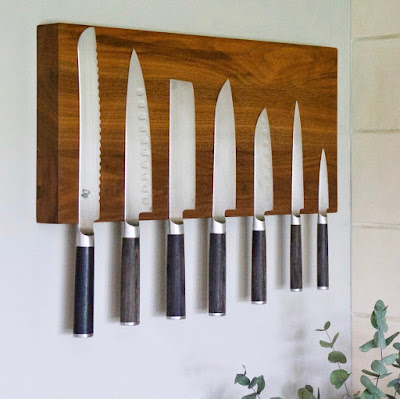large, tall walnut knife rack with seven knives hanging on it