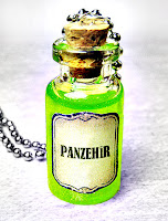 Ağzı mantar ile kapatılmış ucunda zincir takılı küçük bir şişe içinde yeşil renkli panzehir sıvısı