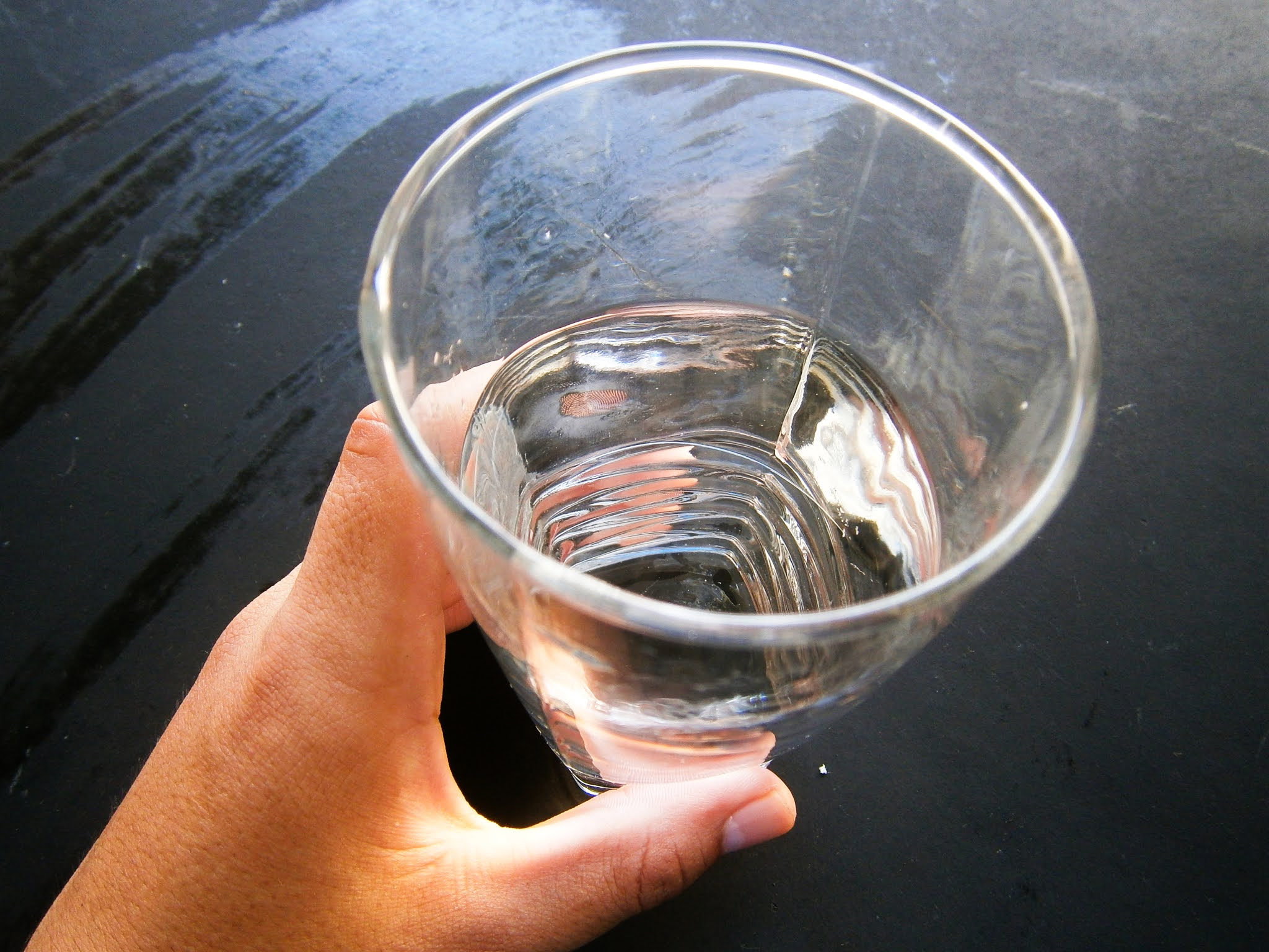 Vaso de agua fresca sostenida de una mano de un joven