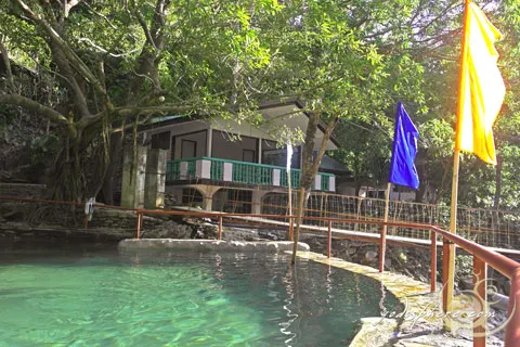 View of the main cottage and old swimming pool and hanging bridge in Calawagan