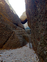 Metal gate entrance way between two large dark stone walls