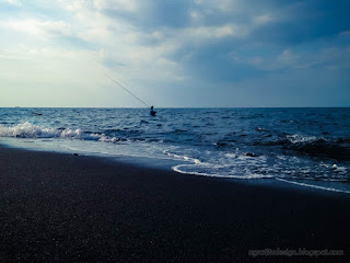 Fisherman Fishing On Seabed Rocky Coast In The Dusk Light Of Tropical Beach At Umeanyar Village North Bali Indonesia