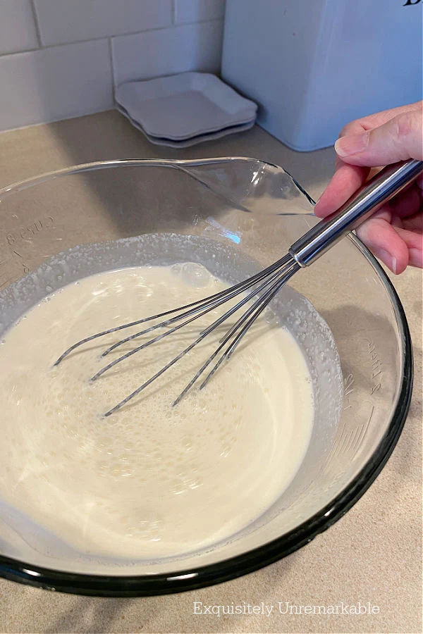 Whisking Ice Cream Recipe ingredients together in a glass bowl
