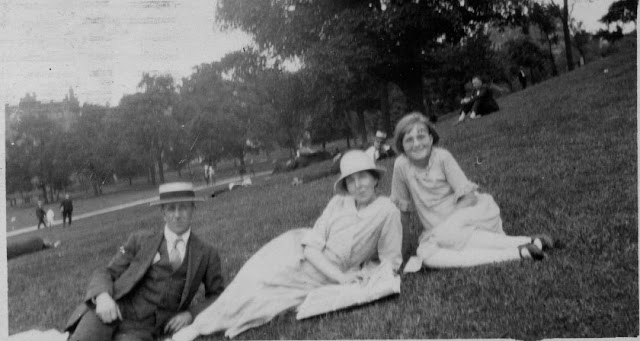 Family of 3 sitting on grass in park
