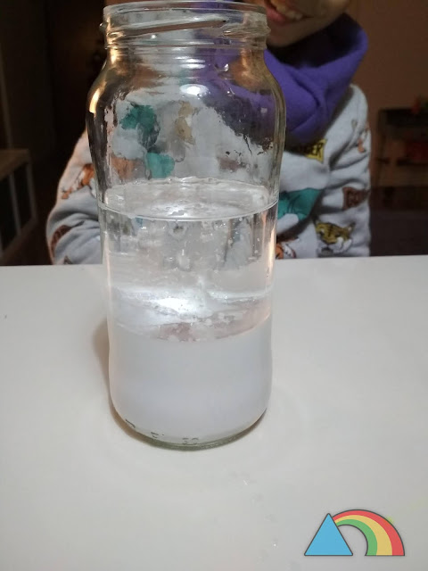 Tormenta de nieve en un bote de cristal, resultado de mezclar agua blanca, aceite mineral y pastillas de vitamina C
