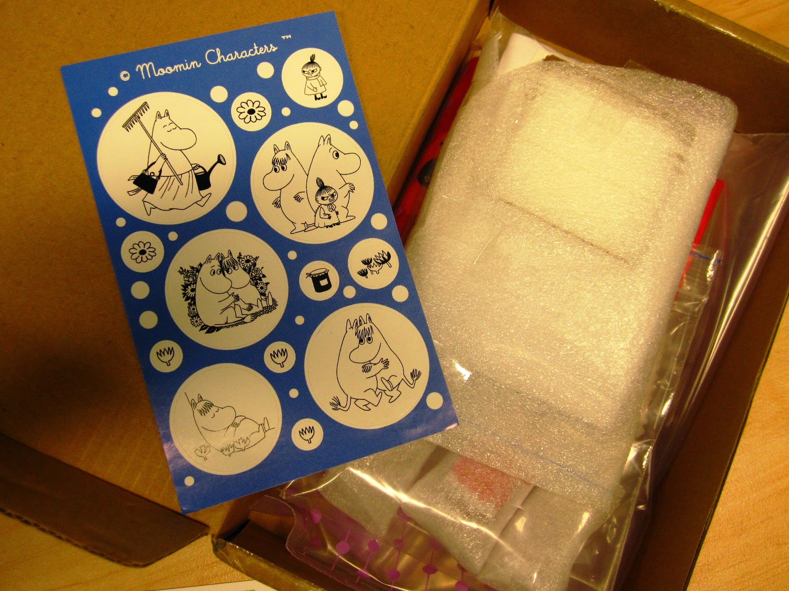 Opened package with Moomin stickers and wrapped contents.