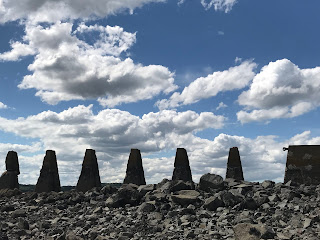 Concrete Pylons built in WWII as an anti-boat barrier with a cloudy sky above them.  Photo by Kevin Nosferatu for the Skulferatu Project.