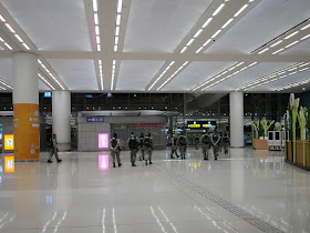 numerous police in riot gear walking through the Hong Kong Port Arrival Hall
