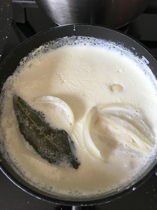 milk with bay, leaf, onion in saucepan