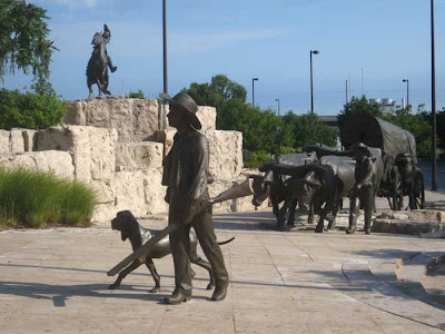 Bronze pioneer wagon with human figures nearby