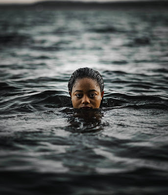 Picture of a black woman with her whole body under water except her head. Learn To Swim and Swimming While Black