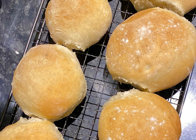 A row of soft white home made bread rolls on a cooling rack created after learning fundamental bread baking tips for beginners.