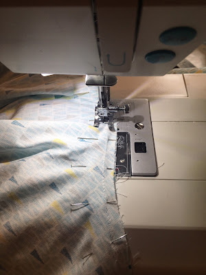 A sewing machine foot going over some fabric
