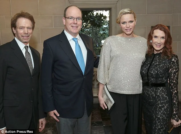 Prince Albert proudly holds up the first public baby gift given to the Monegasque royal couple.