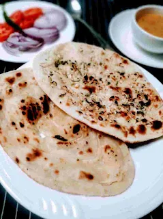 Serving two butter naan dal onion tomato in background