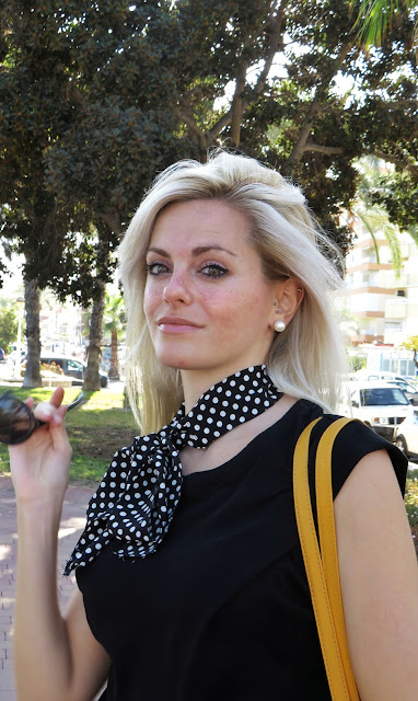 Alejandra Colomera con camiseta negra, pantalón formal negro, lazo en el cuello negro con lunares blancos y complementos mostaza