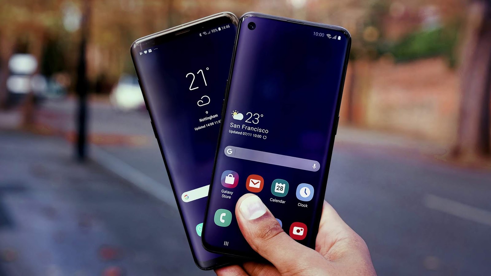  A hand holding two Samsung smartphones, the Galaxy S9 and Galaxy Note 9, with the upcoming Samsung Galaxy S10 and Galaxy Note 10 in the background.