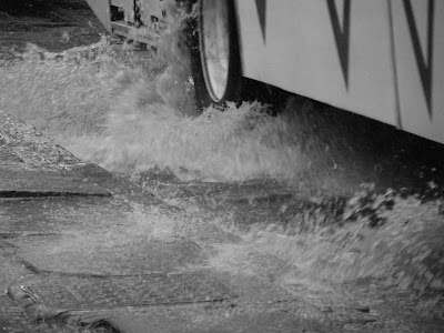 pneus de um ônibus joga água da chuva na calçada