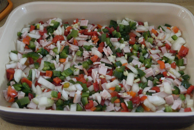 The diced ham, onion, peppers, and garlic in the casserole dish. 