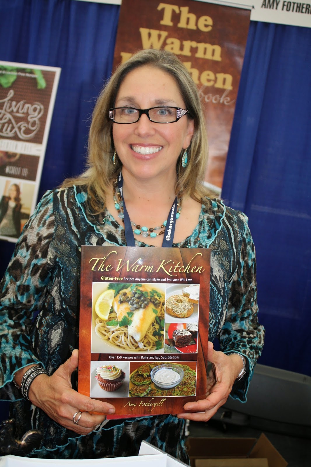Amy from Amythefamilychef.com holding her cookbook "The Warm Kitchen"
