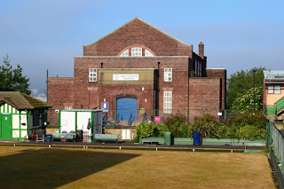 A sun baked bowling green with the Byker Community Centre behind
