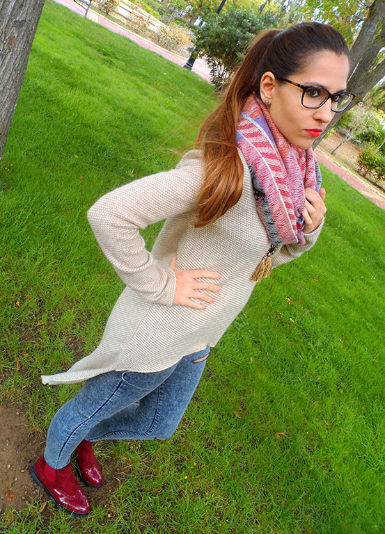 Maxi jersey asimétrico con vaqueros rasgados, botines burdeos, maxi bufanda y reloj