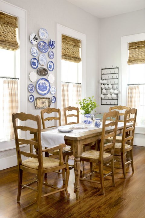 Farmhouse style dining room in a charming cottage. Blue and white plates adorn the wall, ladder back chairs cozy up to the farm table, and check curtains decorate the windows. #diningroom #farmhouse #cottage #homedecor #decoratingideas #countryliving