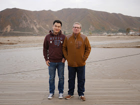 Chinese man and Irishman standing in China with North Korean mountains in the background