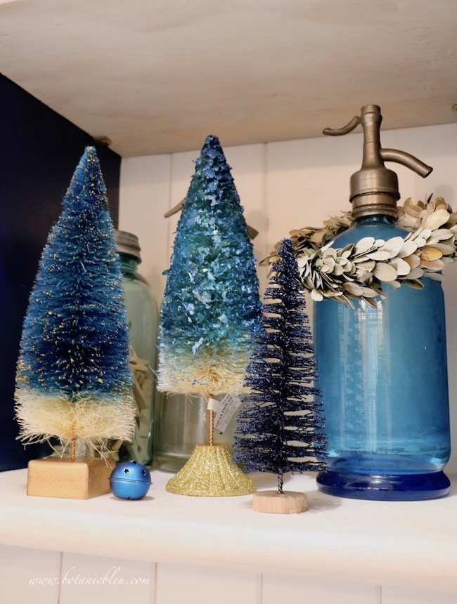 Blue Christmas Laundry Room open shelves decorated with blue bottle brush trees 