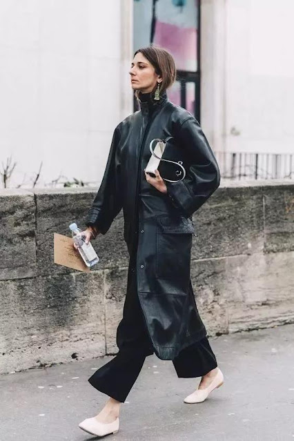 A woman wear a black coat and wide-leg pants.