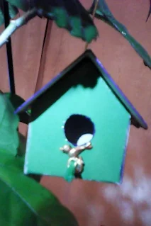 casuta de pasari in miniatura asamblata din carton verde inchis si verede deschis si un ornament pasare sub intrare