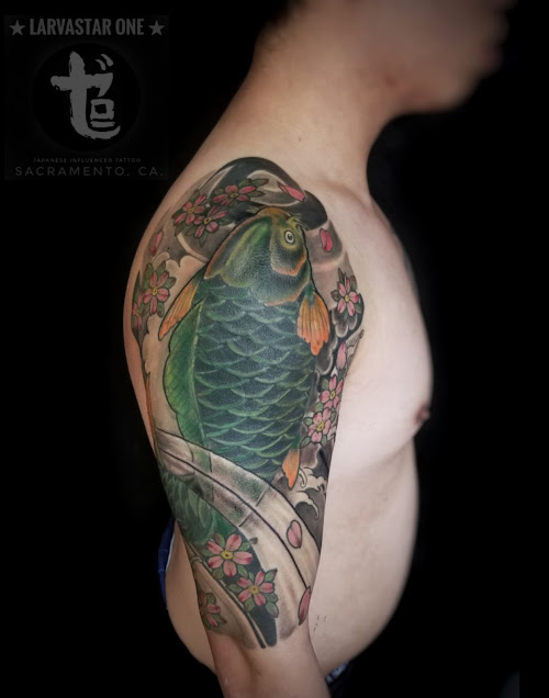front view of black and green tattoo of  a  koi fish with waves and cherries blossom done at zero one ink Sacramento California