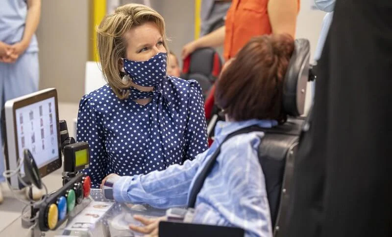 Queen Mathilde wore a navy polka-dot print tie neck blouse from Natan, and polka dot mask, white trousers