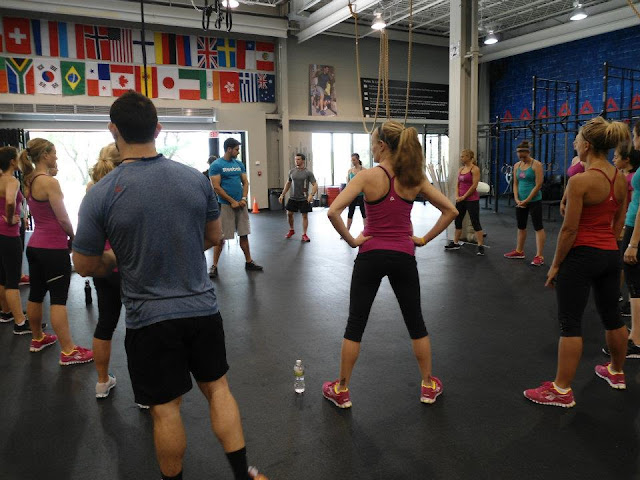 Image of Fitfluential bloggers standing in a circle inside of the Reebok Crossfit ONE facility receiving instruction from one of the trainers