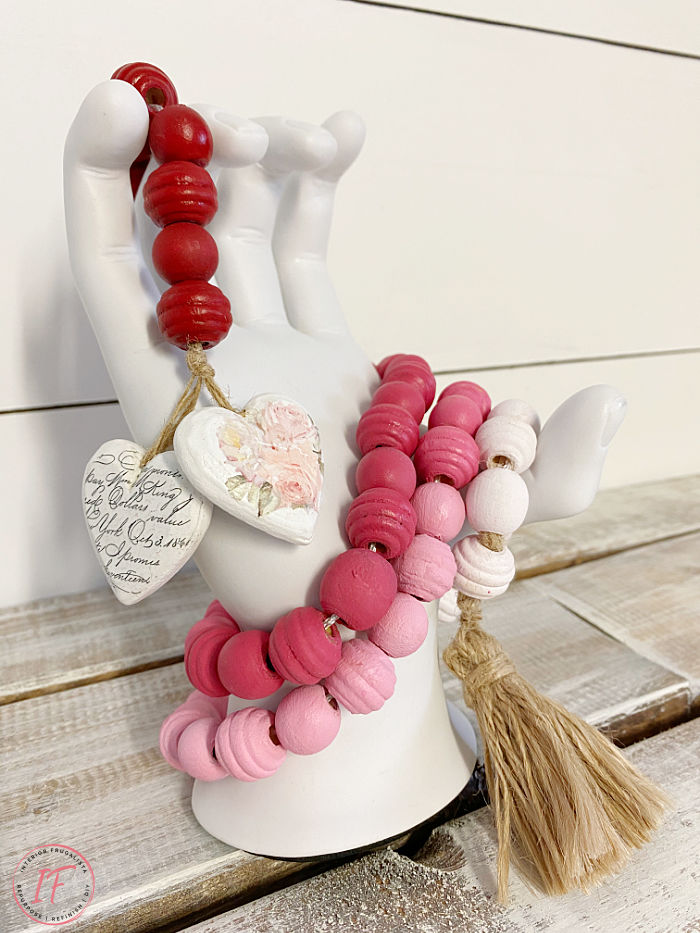 A budget-friendly DIY wooden bead garland painted a pretty gradient pink ombre for Valentine's Day made with a string of dollar store wooden beads.
