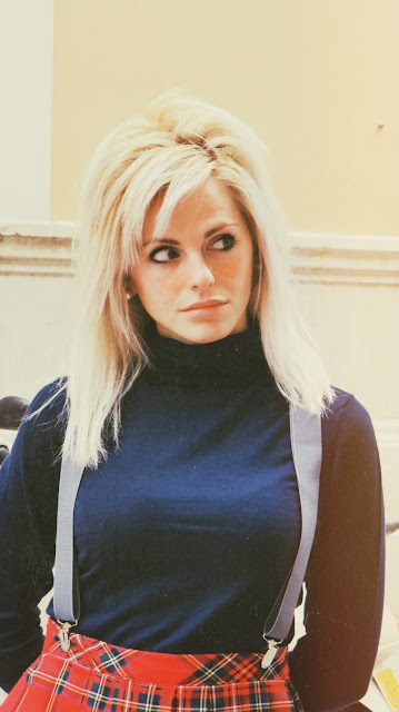 Alejandra Colomera vestida con jersey azul, falda roja cuadros escoceses, tirantes en color gris, calcetas gris y zapatos estilo colegial negro