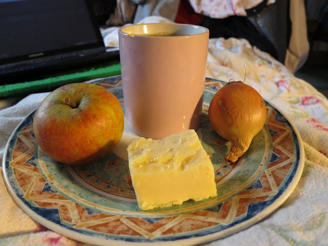 Apple, cheer, a cup of tead and an onion all on a plate.