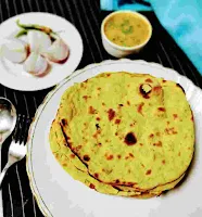 Serving Missi roti in a plate, onion , green chili and dal in background