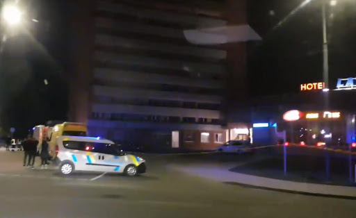 Policijas ekipāža stāv pie tumšas viesnīcas ēkas