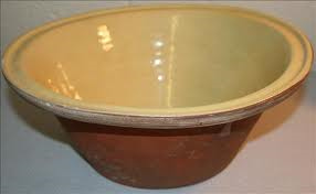 A large inverted cone shaped earthernware bowl, cream on the inside and chestnut brown on the outside.