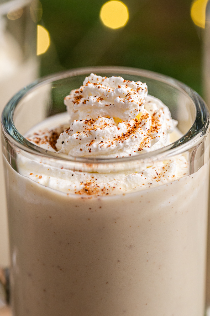 Closeup photo of Keto Eggnog (Dairy-Free & Sugar-Free) in a glass mug with whipped cream and grated nutmeg on top.