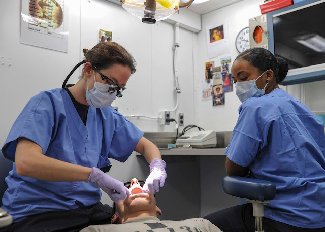 Lt. Kerry Baumann (left), from Cambridge, N.Y., and Hospitalman Apprentice Terra Lamb (right), from Upper Marlboro, Md., perform an oral hygiene check-up on Aviation Structural Mechanic 2nd Class Cory Motley, from Midwest City, Okla., in the dental office of the aircraft carrier USS Theodore Roosevelt (CVN 71). Theodore Roosevelt is operating in the U.S. 7th Fleet area of operations as part of a worldwide deployment en route to its new homeport in San Diego to complete a three-carrier homeport shift. (U.S. Navy Photo by Mass Communication Specialist Seaman Chad M. Trudeau/Released)