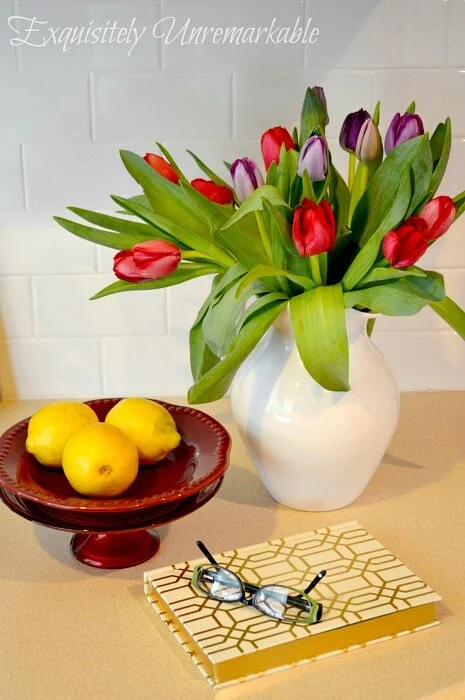 Kitchen Tulips next to cake plate with lemons and a journal on countertop