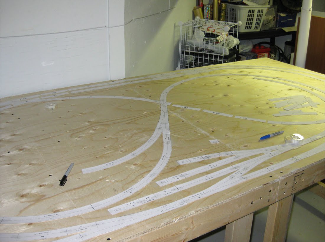 Benchwork made of plywood and lumber with paper track template pieces outlining a railroad track design